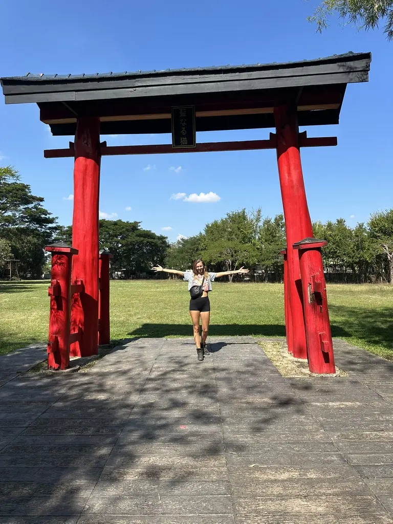 Woman rider under the torii gate at Nekoemon Cafe, a Japanese garden stop on a Thai motorcycle ride